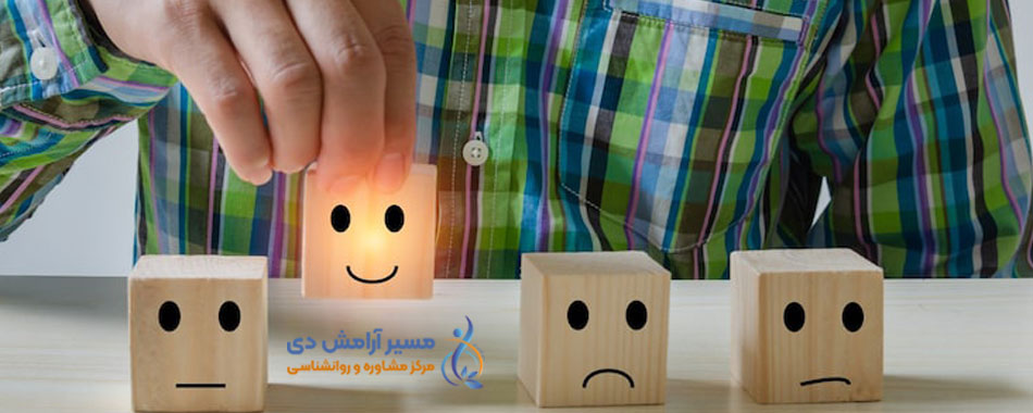 دستی که یک مکعب چوبی درخشان با چهره خندان را از میان مکعب‌های دارای چهره‌های بی‌تفاوت و غمگین برمی‌دارد.