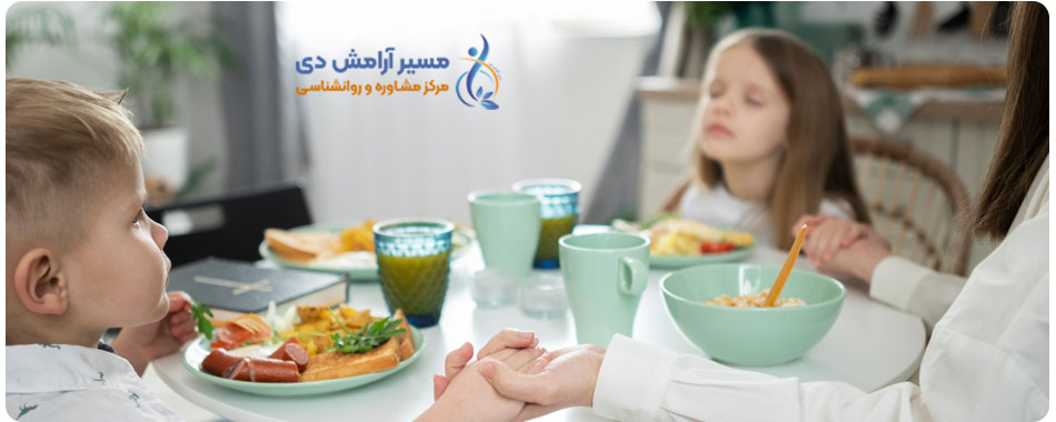 یک خانواده شامل دو زن و یک پسر بچه که در حال تمرین ذهن آگاهی هنگام غذا خوردن هستند و چشمانشان بسته است. آنها میوه‌های تازه را با آرامش میل می‌کنند.